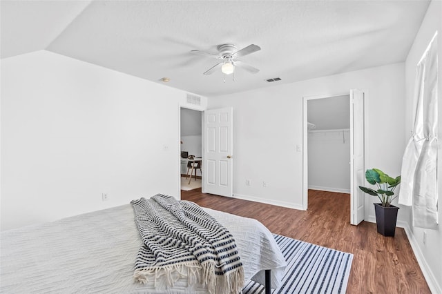 bedroom with a walk in closet, wood finished floors, visible vents, and a closet