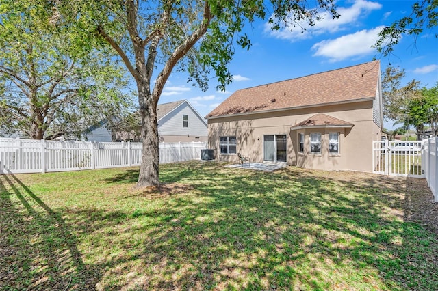 back of house featuring stucco siding, a lawn, a fenced backyard, and a gate