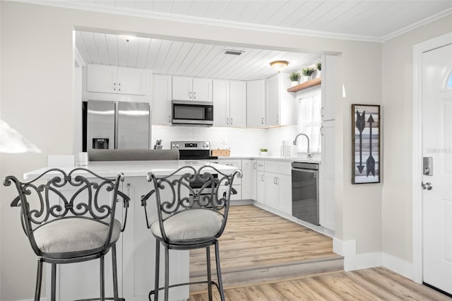 kitchen featuring tasteful backsplash, visible vents, a breakfast bar, stainless steel appliances, and white cabinetry