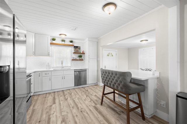 kitchen featuring open shelves, crown molding, light countertops, appliances with stainless steel finishes, and a sink