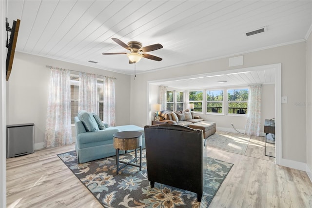 living room with wood finished floors, a ceiling fan, visible vents, and ornamental molding