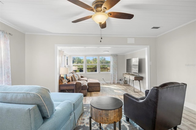 living room featuring wood finished floors, baseboards, visible vents, ceiling fan, and ornamental molding