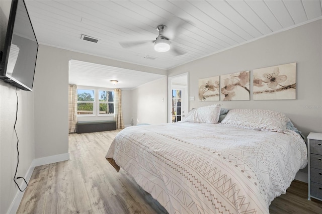 bedroom with visible vents, wood finished floors, baseboards, and ornamental molding