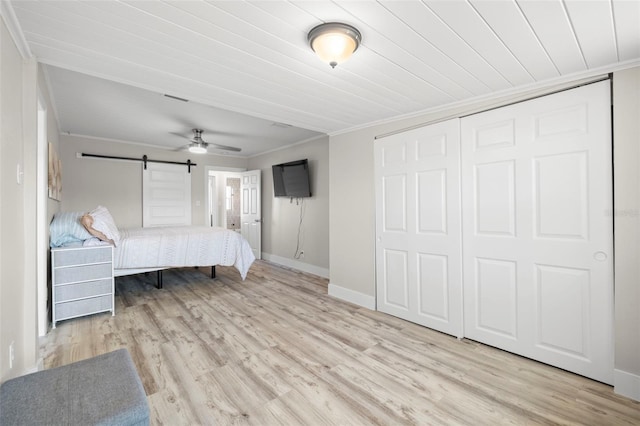 bedroom with crown molding, wood finished floors, baseboards, and a closet