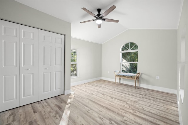 unfurnished bedroom featuring lofted ceiling, multiple windows, wood finished floors, and baseboards