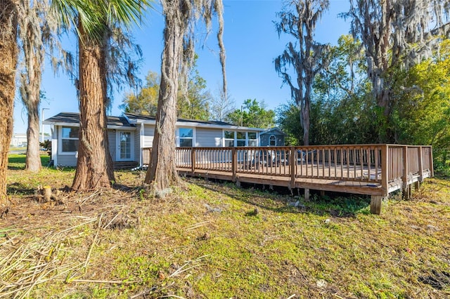 back of property with a wooden deck and a lawn