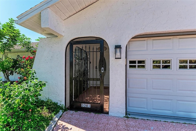 doorway to property featuring stucco siding and a garage