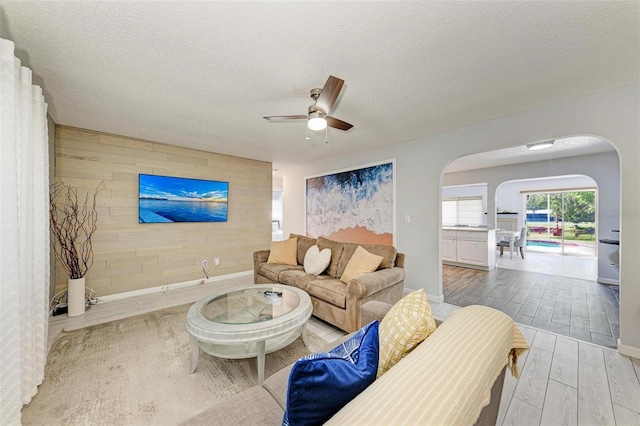 living area featuring wooden walls, a textured ceiling, an accent wall, and wood tiled floor