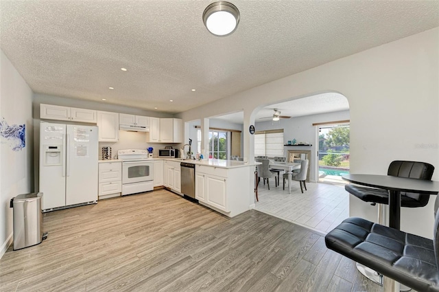 kitchen featuring light wood finished floors, under cabinet range hood, light countertops, appliances with stainless steel finishes, and white cabinetry