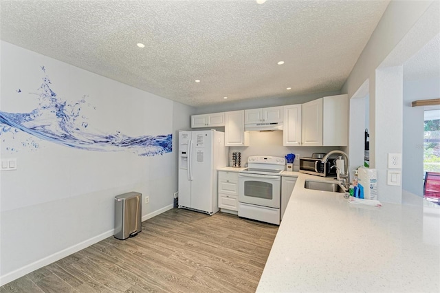 kitchen with under cabinet range hood, light wood-type flooring, light countertops, white appliances, and a sink