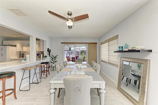 dining area with visible vents, a textured ceiling, ceiling fan, and wood tiled floor