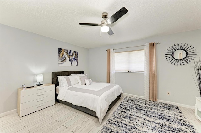 bedroom with baseboards, ceiling fan, a textured ceiling, and light wood-style floors