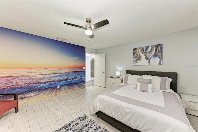 bedroom featuring visible vents, a textured ceiling, ceiling fan, and wood finished floors