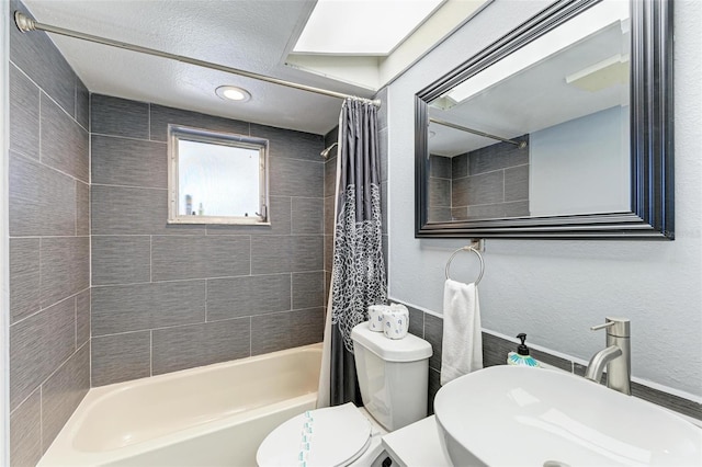 full bathroom with shower / tub combo, toilet, a textured wall, and a sink