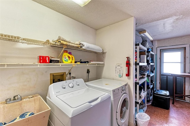 washroom featuring tile patterned floors, a sink, a textured ceiling, separate washer and dryer, and laundry area