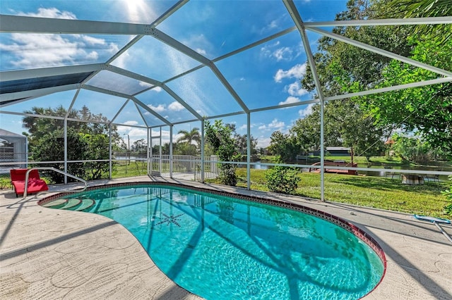 outdoor pool with glass enclosure, a patio, and a water view