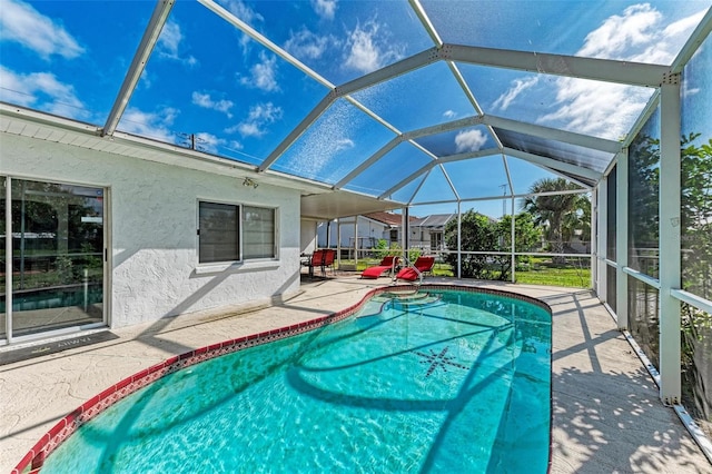 outdoor pool featuring glass enclosure and a patio