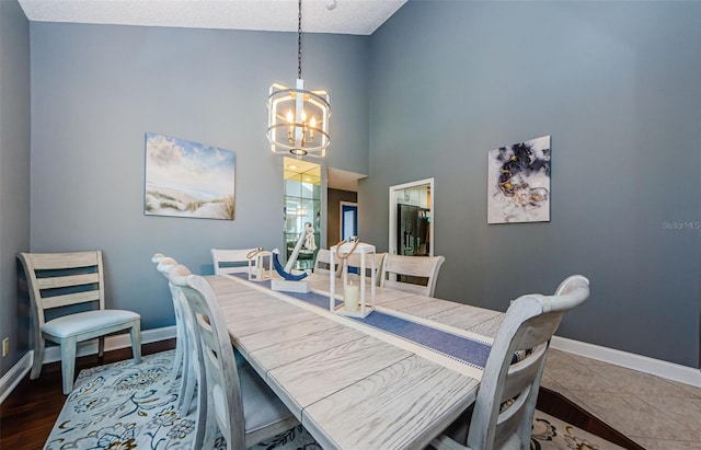 dining room featuring baseboards, an inviting chandelier, and a towering ceiling