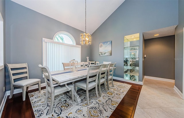 dining space with a chandelier, high vaulted ceiling, light wood-type flooring, and baseboards