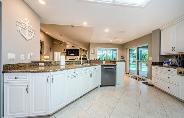 kitchen featuring dishwasher, light tile patterned floors, dark stone countertops, white cabinets, and a sink