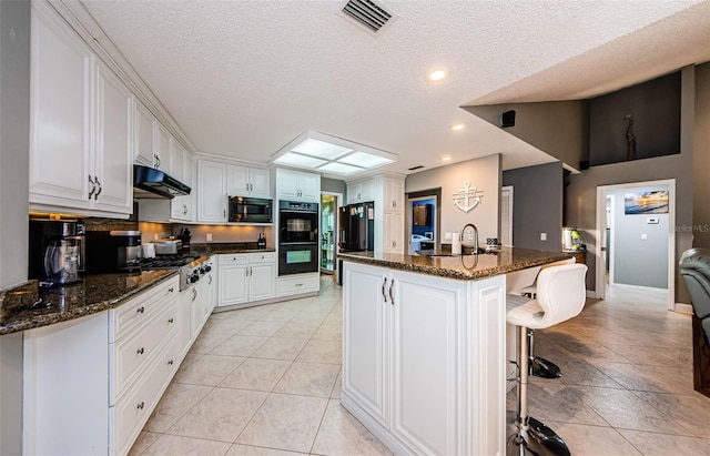 kitchen with visible vents, under cabinet range hood, light tile patterned flooring, black appliances, and a sink