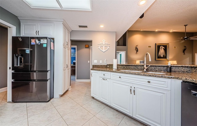 kitchen featuring dishwashing machine, a ceiling fan, dark stone counters, a sink, and fridge with ice dispenser