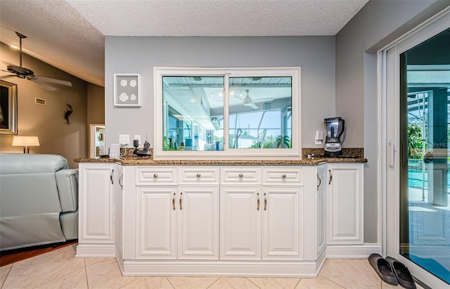 kitchen with white cabinetry, dark stone countertops, a textured ceiling, and ceiling fan