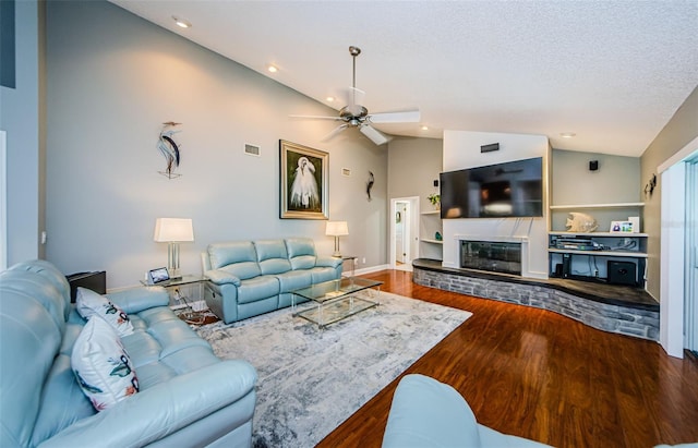 living room with visible vents, a ceiling fan, a glass covered fireplace, wood finished floors, and vaulted ceiling