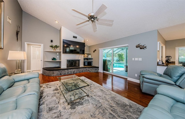 living area with visible vents, a glass covered fireplace, wood finished floors, baseboards, and ceiling fan