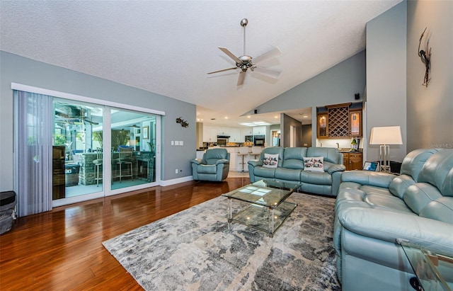 living area featuring baseboards, wood finished floors, a textured ceiling, high vaulted ceiling, and a ceiling fan