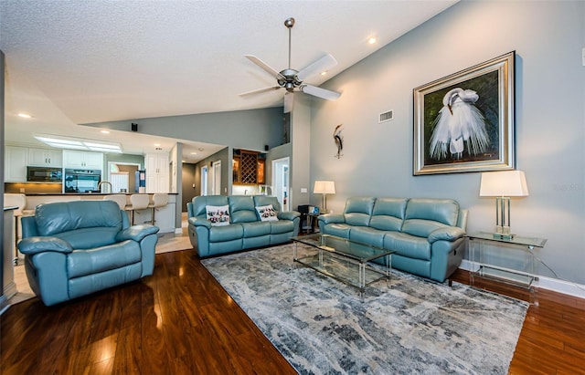 living area featuring visible vents, ceiling fan, baseboards, vaulted ceiling, and wood finished floors