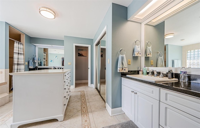 bathroom with a sink, baseboards, two vanities, and tile patterned floors