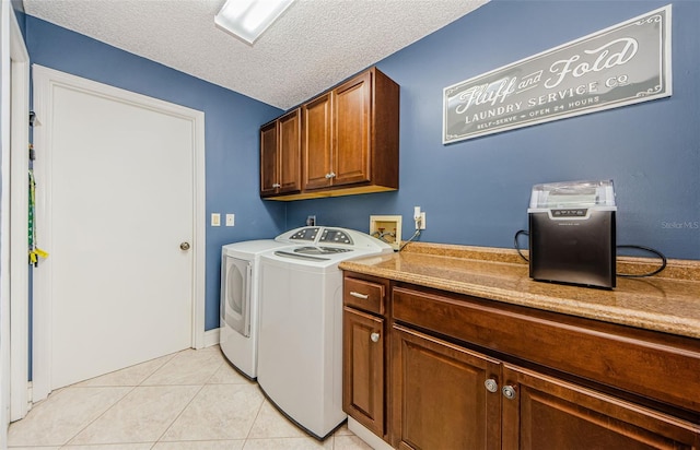 clothes washing area featuring light tile patterned floors, cabinet space, a textured ceiling, and washer and clothes dryer