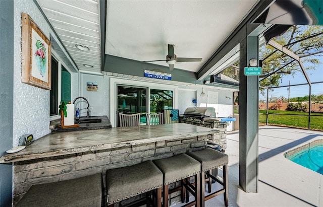 view of patio featuring glass enclosure, exterior kitchen, area for grilling, a sink, and outdoor dry bar