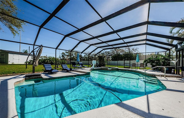 view of pool featuring an outbuilding, a shed, a patio area, and glass enclosure