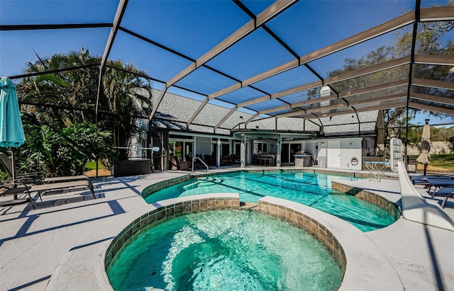 view of pool with glass enclosure, a pool with connected hot tub, and a patio area