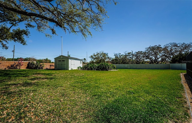 view of yard with an outdoor structure, a fenced backyard, and a shed