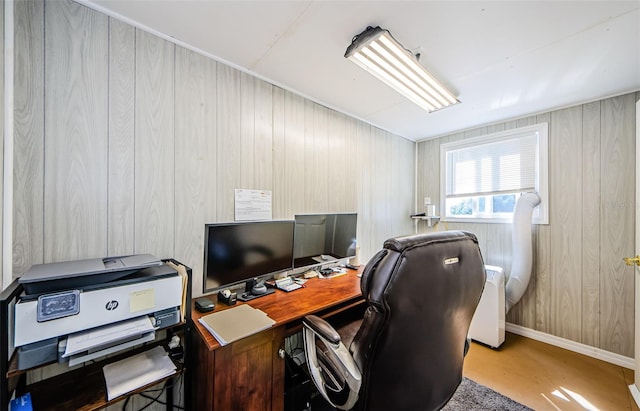 office space with baseboards and wood walls