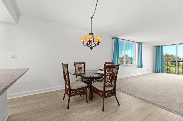 dining room with plenty of natural light, light wood-style flooring, baseboards, and an inviting chandelier