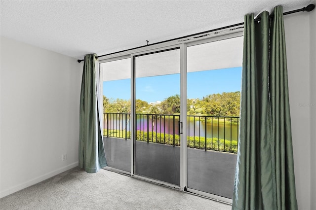 carpeted spare room with a wall of windows, baseboards, a water view, and a textured ceiling