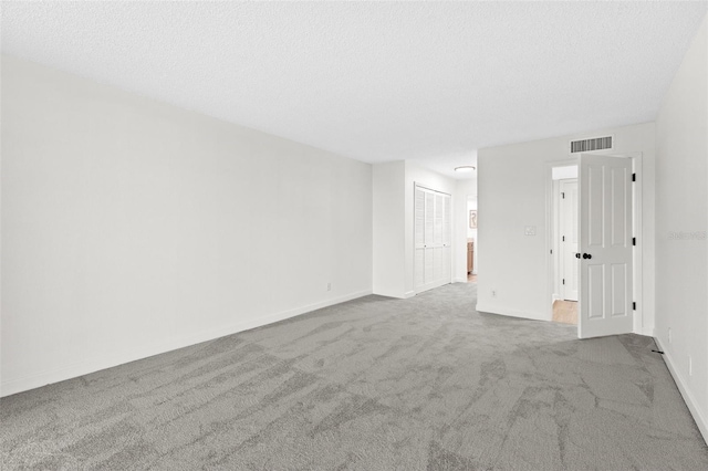 carpeted empty room with visible vents, a textured ceiling, and baseboards