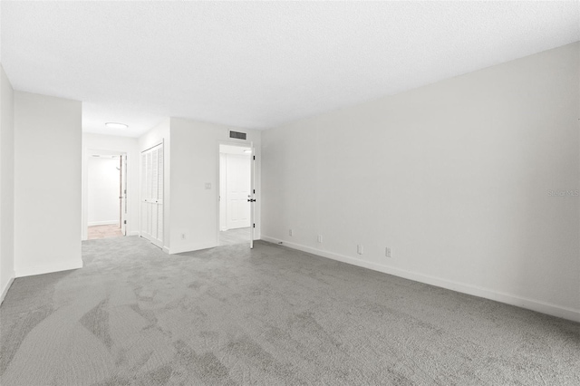 carpeted spare room featuring visible vents, baseboards, and a textured ceiling