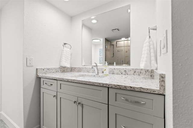 bathroom with visible vents, baseboards, vanity, and a textured wall