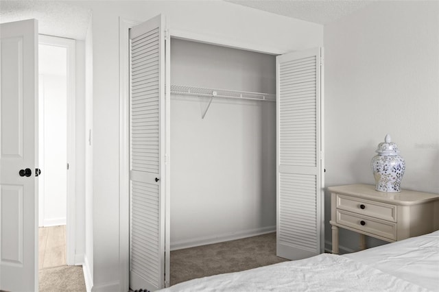 bedroom with a closet, a textured ceiling, and carpet flooring