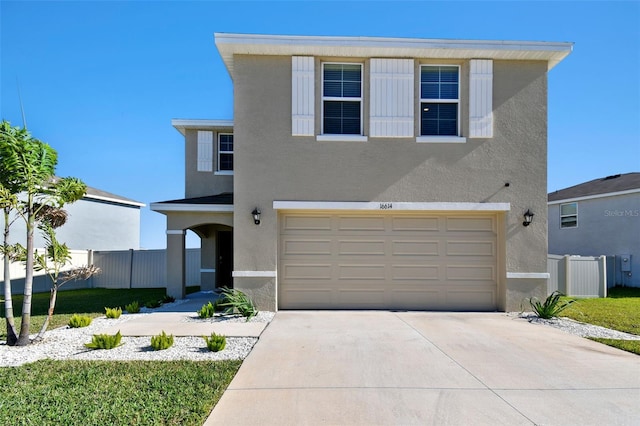 traditional home featuring a garage, fence, driveway, and stucco siding