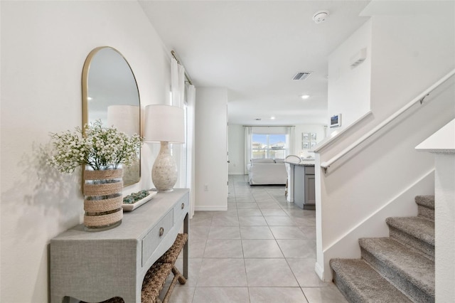 foyer with light tile patterned floors, visible vents, baseboards, and stairs