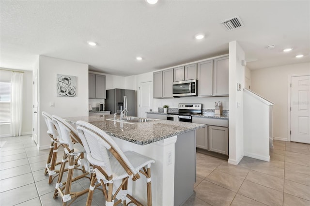 kitchen featuring visible vents, appliances with stainless steel finishes, gray cabinetry, and a sink