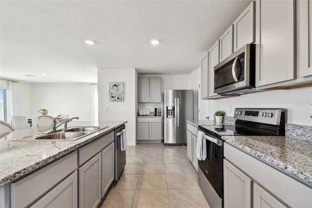 kitchen featuring a textured ceiling, light tile patterned floors, appliances with stainless steel finishes, and a sink