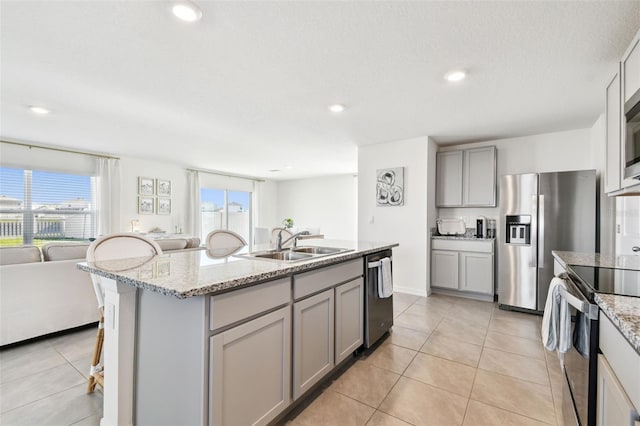 kitchen featuring gray cabinetry, open floor plan, light tile patterned flooring, stainless steel appliances, and a sink