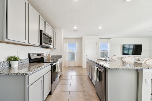 kitchen featuring visible vents, a sink, light tile patterned floors, appliances with stainless steel finishes, and a kitchen island with sink